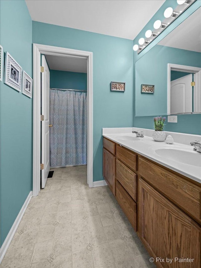 full bathroom with double vanity, baseboards, and a sink