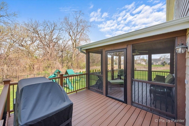wooden deck with a sunroom, area for grilling, a playground, and fence