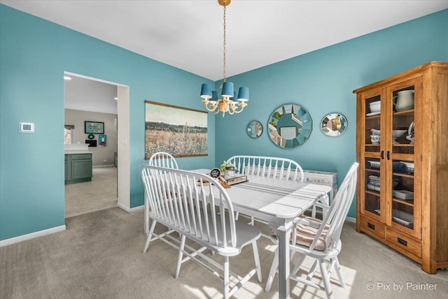 dining area featuring a notable chandelier, light carpet, and baseboards