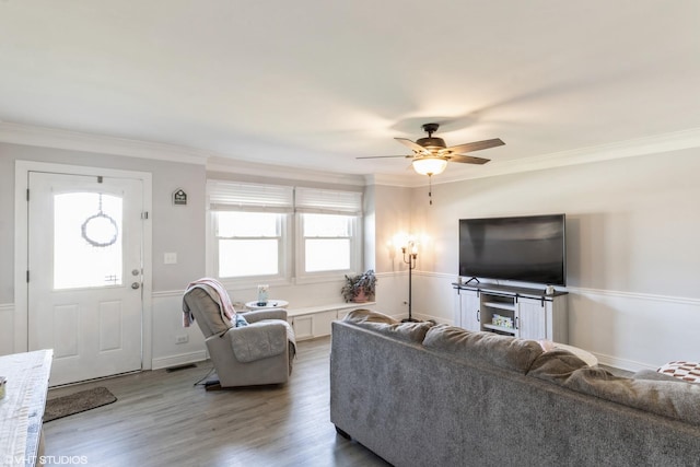 living room with ceiling fan, crown molding, wood finished floors, and a wainscoted wall