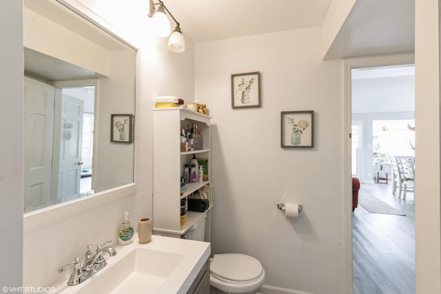 bathroom with toilet, baseboards, vanity, and wood finished floors