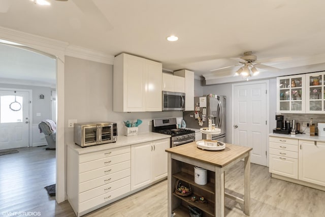 kitchen with stainless steel appliances, ornamental molding, white cabinetry, light wood-type flooring, and recessed lighting