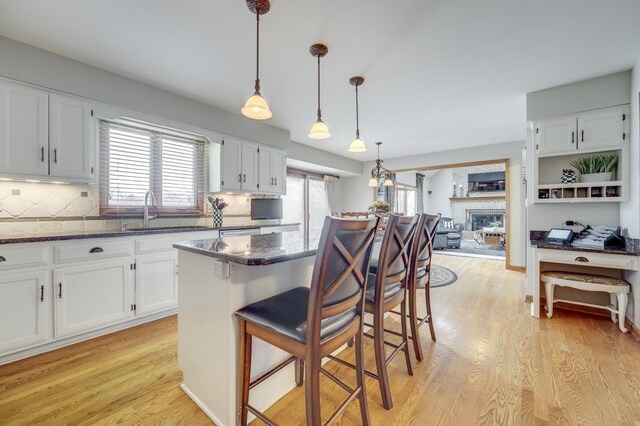 2624 Haddassah Dr, Naperville, IL 60565 - kitchen with a breakfast bar area, light wood-style flooring, white cabinetry, and a sink