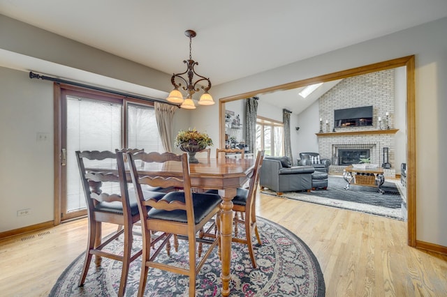 2624 Haddassah Dr, Naperville, IL 60565 - dining area with a chandelier, a fireplace, light wood-type flooring, and vaulted ceiling