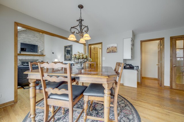 2624 Haddassah Dr, Naperville, IL 60565 - dining space with baseboards, light wood finished floors, a chandelier, and a brick fireplace
