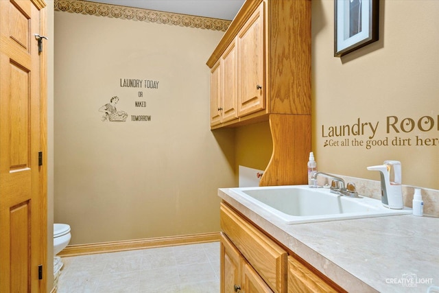 clothes washing area with light tile patterned floors, a sink, and baseboards