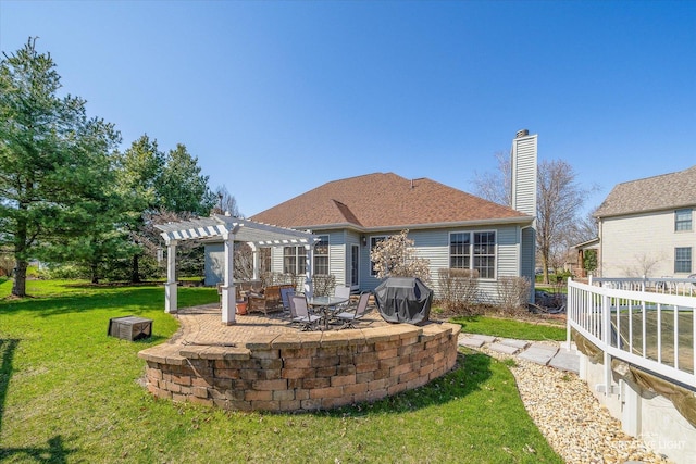 rear view of house featuring a pergola, a lawn, a patio, a chimney, and a shingled roof