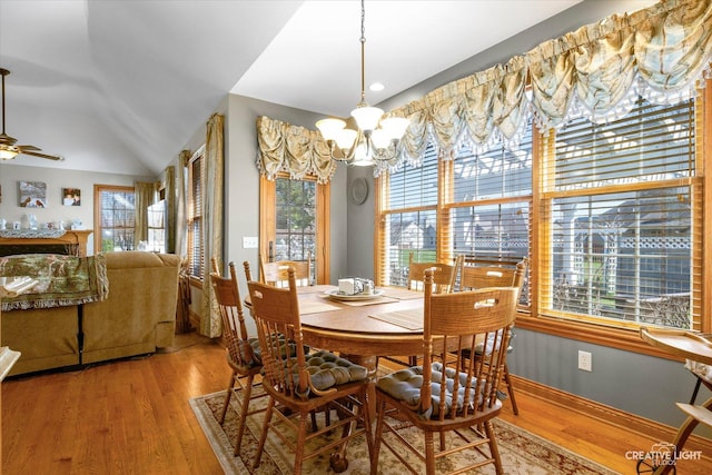 dining area featuring baseboards, light wood finished floors, ceiling fan with notable chandelier, and vaulted ceiling