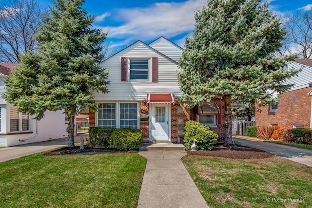townhome / multi-family property with brick siding, fence, and a front lawn