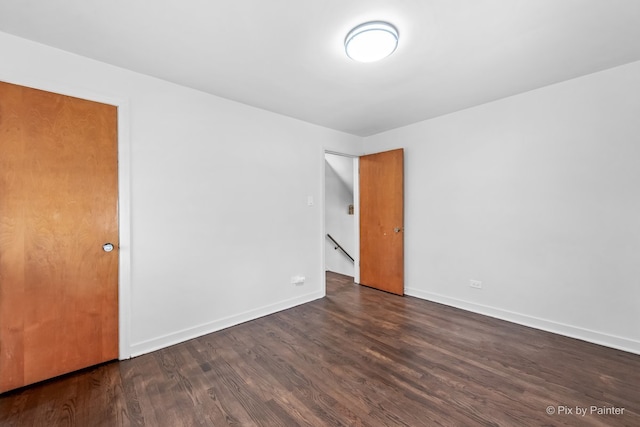 unfurnished room featuring dark wood-type flooring and baseboards