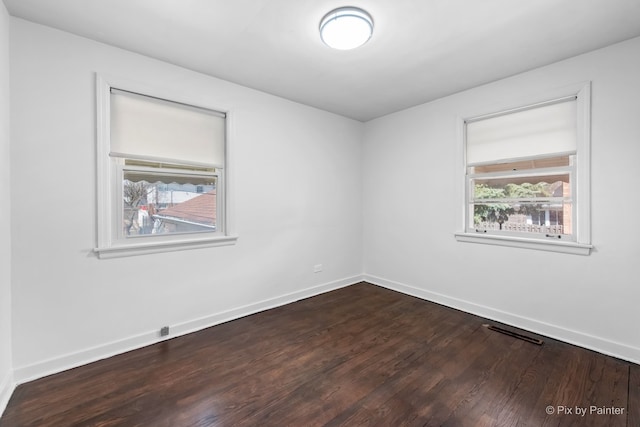 unfurnished room with dark wood-style floors, baseboards, and visible vents