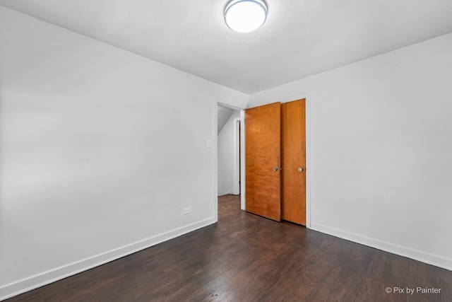 unfurnished room featuring dark wood-style flooring and baseboards
