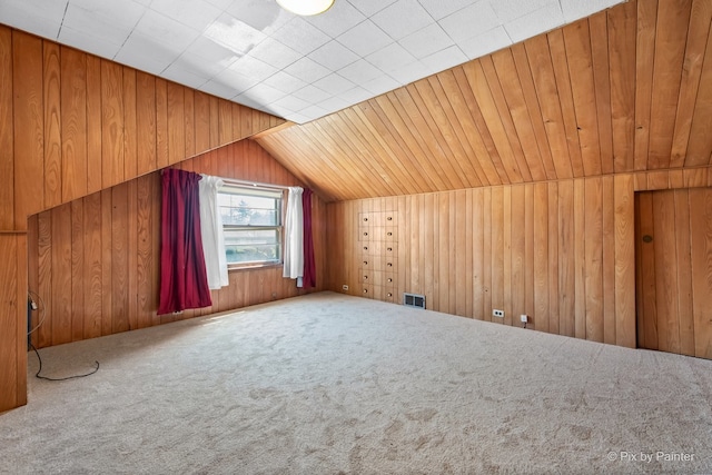 bonus room with wooden walls, carpet floors, visible vents, and lofted ceiling