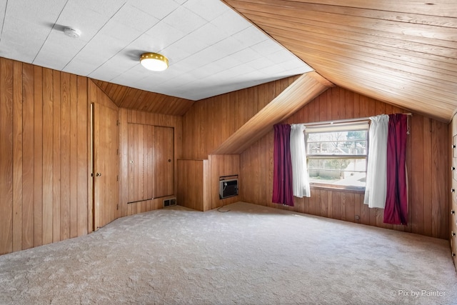 additional living space featuring wood walls, carpet flooring, visible vents, and vaulted ceiling