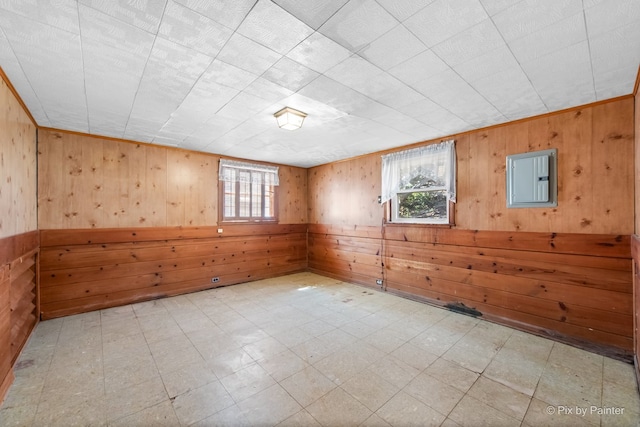 empty room featuring tile patterned floors, a healthy amount of sunlight, wood walls, and electric panel