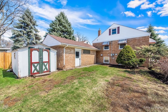 rear view of house with a shed, an outbuilding, a lawn, fence, and brick siding