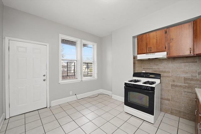 6611 S Peoria St, Chicago, IL 60621 - kitchen featuring gas range oven, under cabinet range hood, light tile patterned floors, brown cabinetry, and baseboards
