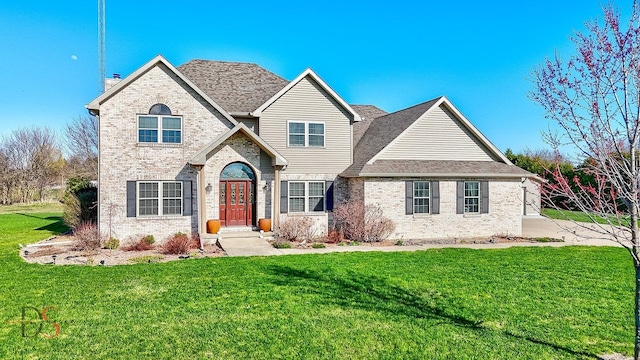 traditional home featuring a front yard and brick siding