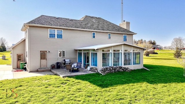 rear view of property featuring a chimney, a patio area, a shingled roof, a sunroom, and a lawn