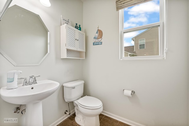 half bath featuring toilet, baseboards, a sink, and tile patterned flooring