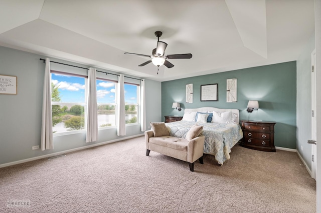 carpeted bedroom featuring baseboards, ceiling fan, a tray ceiling, and visible vents