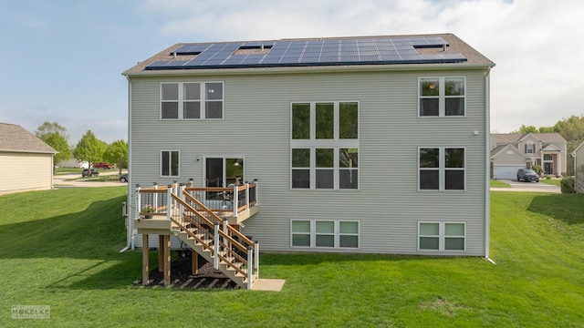 back of house with stairs, roof mounted solar panels, a wooden deck, and a lawn