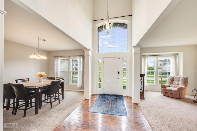 entrance foyer with decorative columns, a notable chandelier, and plenty of natural light