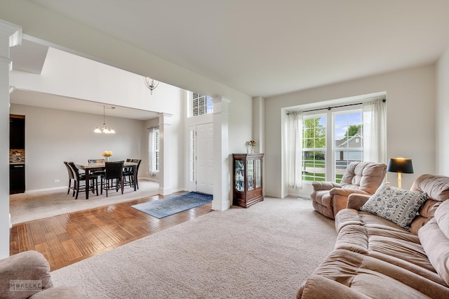 carpeted living area with baseboards, wood finished floors, and a notable chandelier