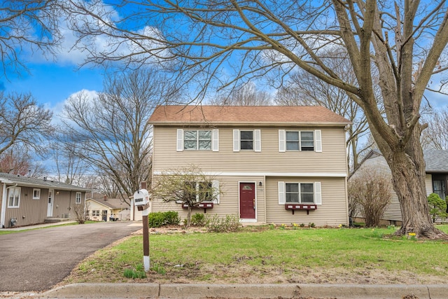 colonial-style house featuring a front lawn and asphalt driveway
