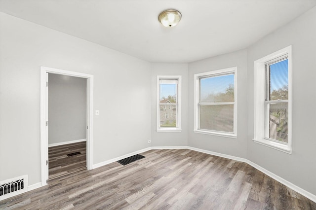 spare room featuring visible vents, wood finished floors, and baseboards