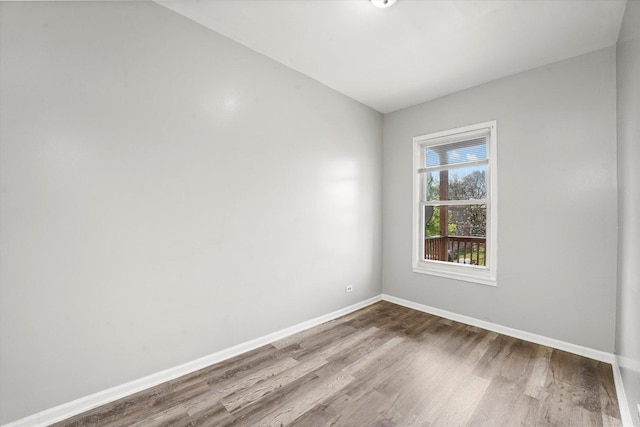 empty room with vaulted ceiling, baseboards, and wood finished floors