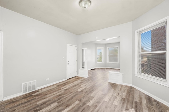 empty room featuring visible vents, wood finished floors, and baseboards