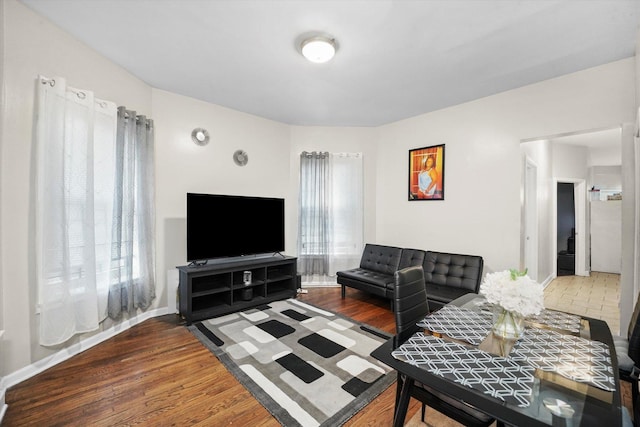 living area with baseboards, plenty of natural light, and wood finished floors