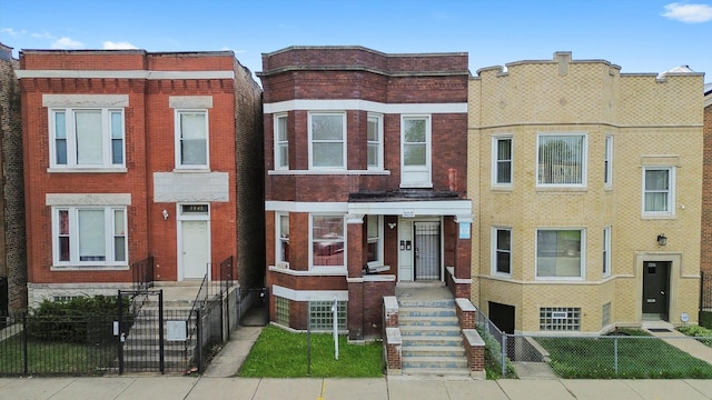 multi unit property with a fenced front yard and brick siding