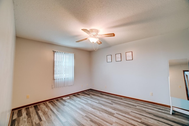 unfurnished room featuring baseboards, a ceiling fan, wood finished floors, and a textured ceiling