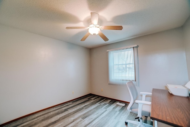 unfurnished office with ceiling fan, a textured ceiling, wood finished floors, and baseboards