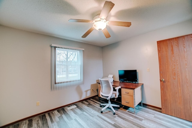 home office with a textured ceiling, light wood finished floors, baseboards, and a ceiling fan