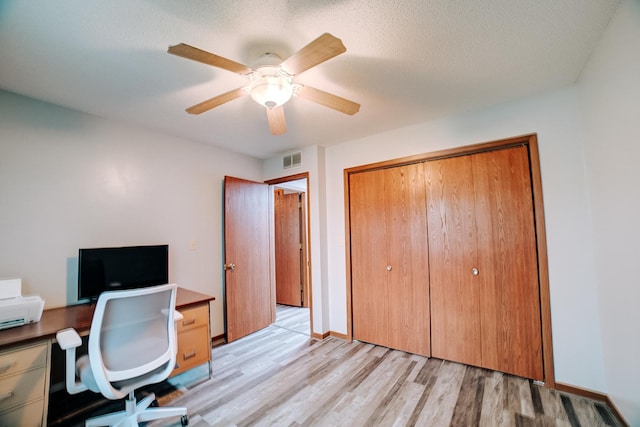 office space featuring light wood finished floors, visible vents, baseboards, and ceiling fan