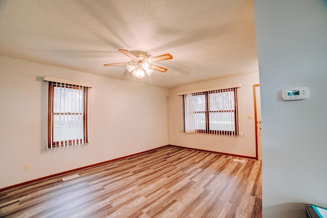 spare room featuring a wealth of natural light, light wood-style flooring, a textured ceiling, and a ceiling fan