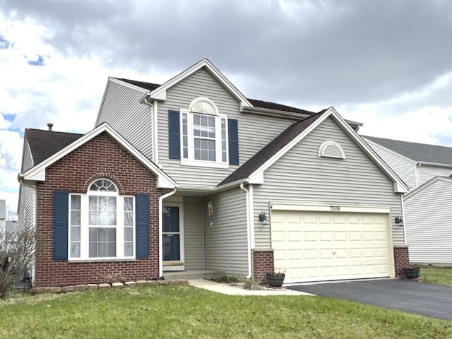 traditional-style home featuring an attached garage, brick siding, driveway, and a front yard