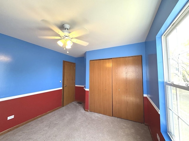 unfurnished bedroom featuring carpet floors, a closet, and ceiling fan