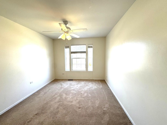 carpeted spare room with ceiling fan and baseboards