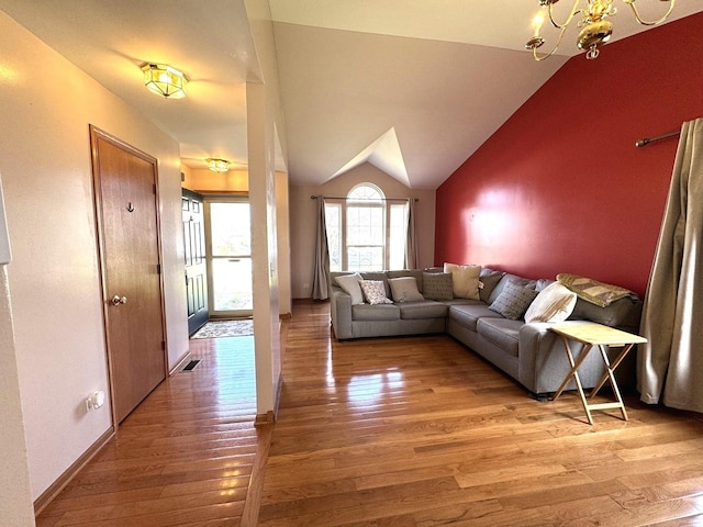 living area featuring lofted ceiling, an inviting chandelier, visible vents, and light wood-type flooring