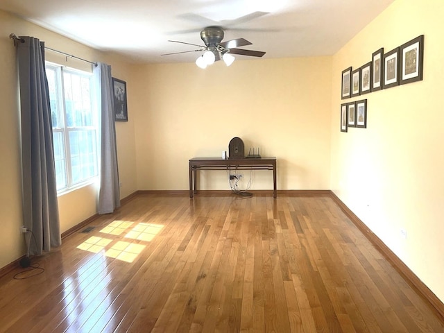 interior space featuring wood-type flooring, visible vents, baseboards, and ceiling fan