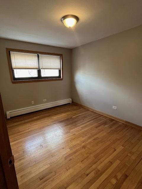 4416 N Kostner Ave Unit 2B, Chicago, IL 60630 - empty room featuring a baseboard heating unit, wood finished floors, and baseboards
