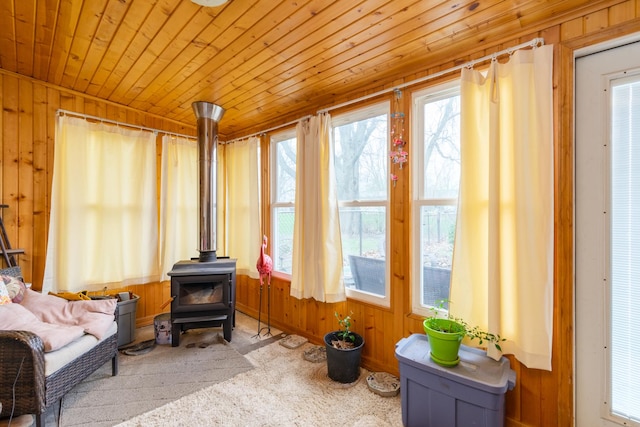 sitting room with a wood stove, wooden walls, wooden ceiling, and carpet floors