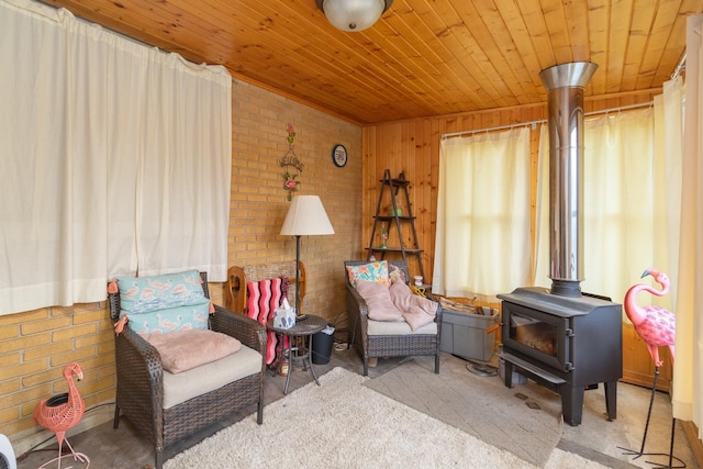 sitting room featuring a wood stove, brick wall, and wood ceiling
