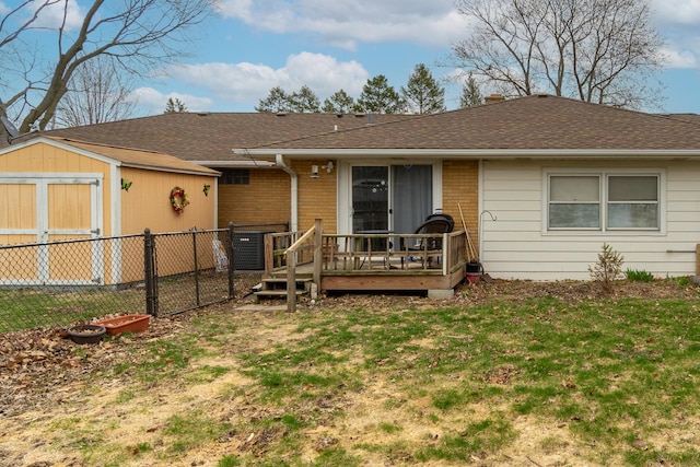 view of front facade featuring a storage shed, an outdoor structure, fence, a front lawn, and a deck
