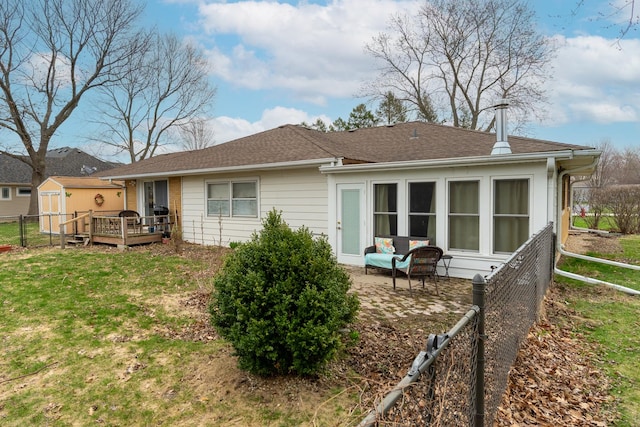 back of house with a storage shed, an outdoor structure, a lawn, fence, and a deck