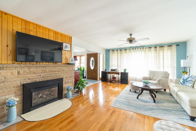 living room featuring light wood-style flooring, a ceiling fan, and a fireplace